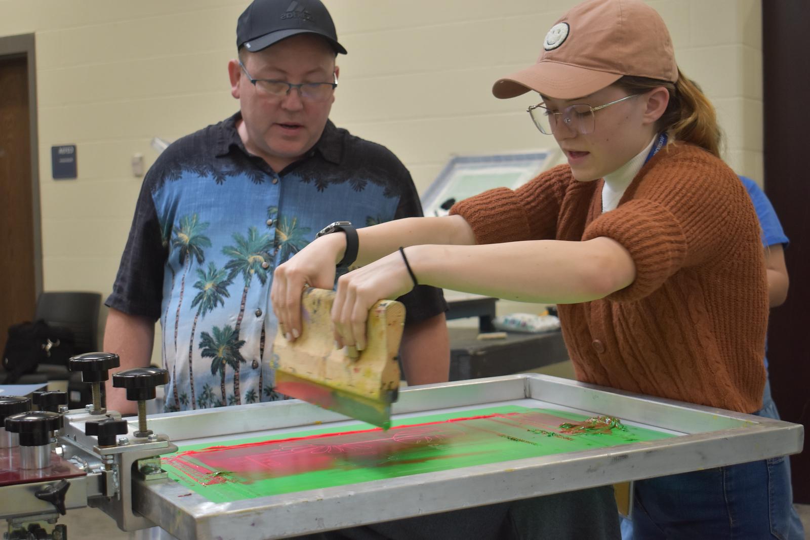 A techmester participant mixing paint while a professor observes