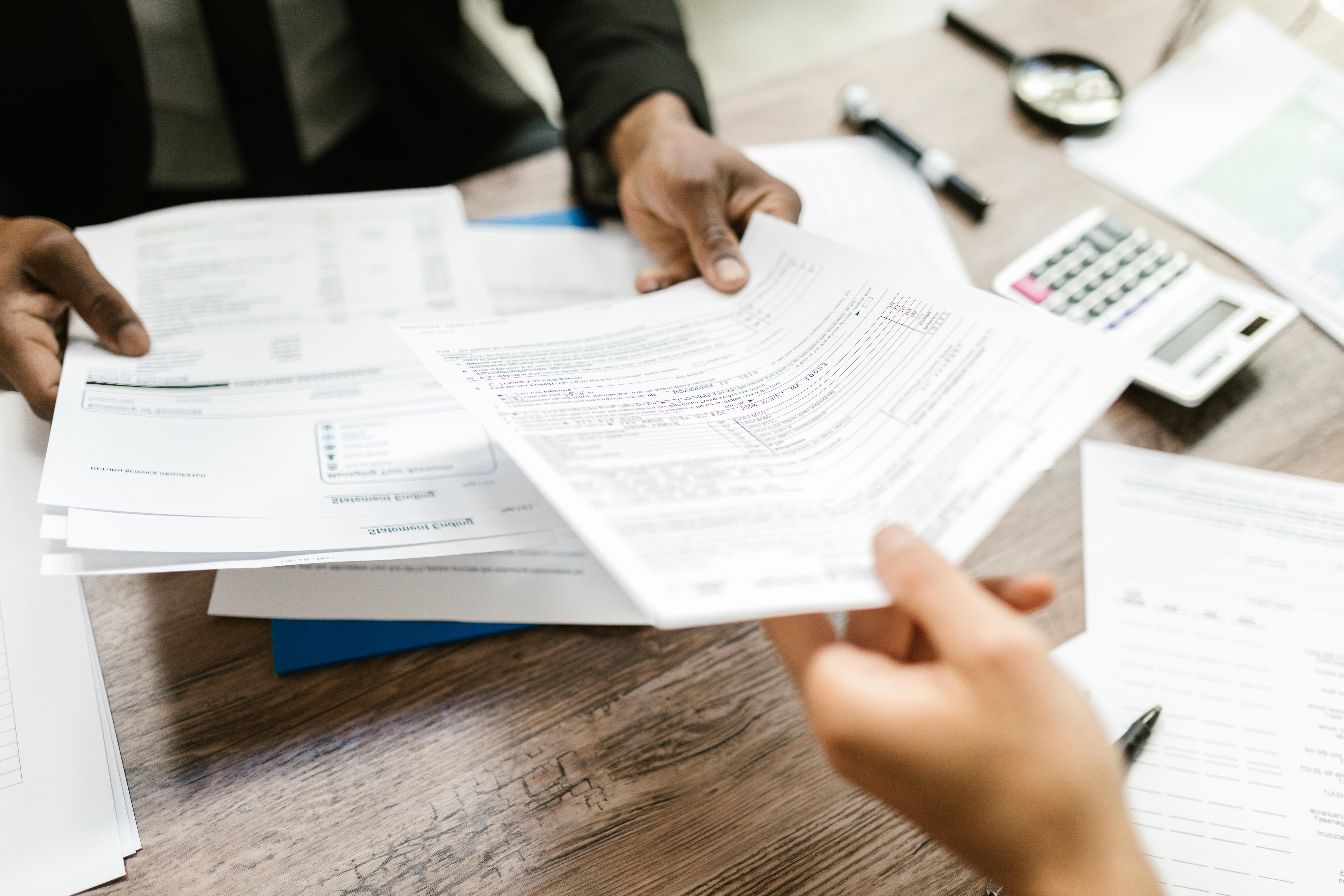 Hands passing paperwork across a desk.