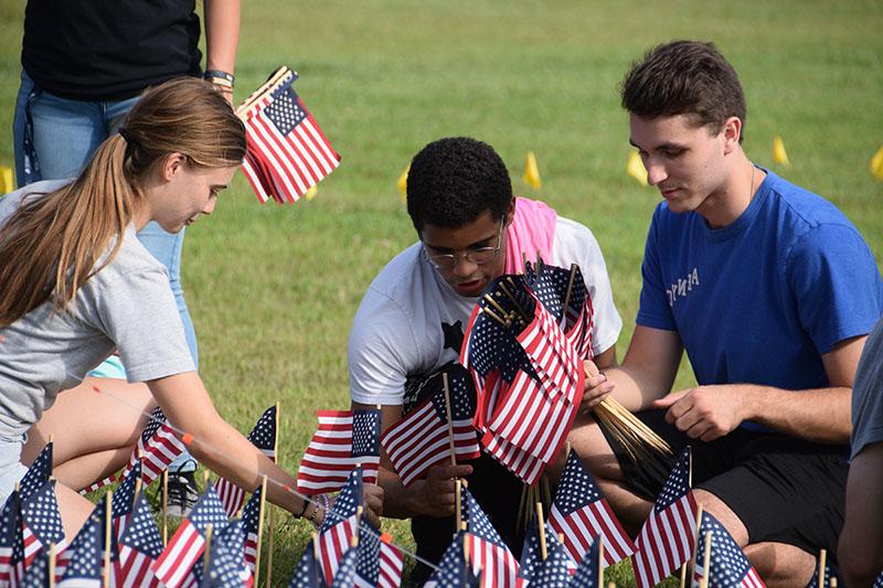 Three students picking up flags off the ground